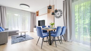 Un salon moderne comprenant un coin repas, de grandes fenêtres et un téléviseur à écran plat.