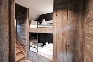 A bunk bed room with wooden walls and a staircase.