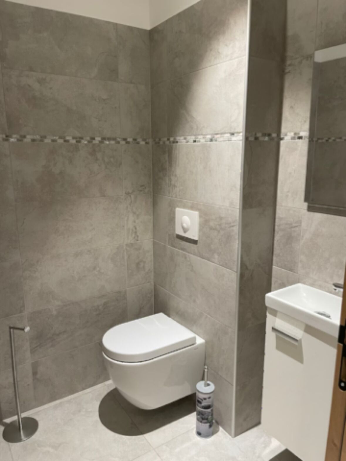 Une salle de bain moderne équipée de toilettes, d’un lavabo et d’un espace douche.
