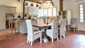 A kitchen with a wooden ceiling, white cabinets, and a dining area with wicker chairs and a wooden table. - Luxury Villa in Dordogne with Pool & Privacy (Port-Sainte-Foy-et-Ponchapt)