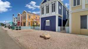 Farverige huse i række med grusvej og en klar blå himmel.