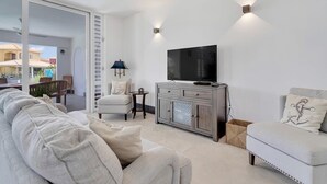 En moderne stue med en sofa, et fjernsyn og et lille bord.