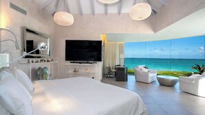Ett modernt hotellrum med en stor säng, en platt-TV, ett skrivbord och utsikt över havet.