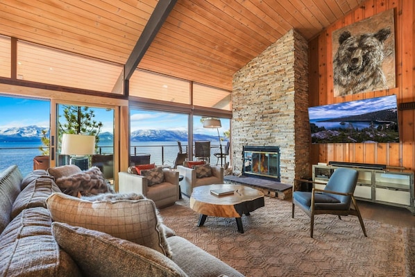 A spacious living area with a stone fireplace, comfortable seating, and a large TV screen.