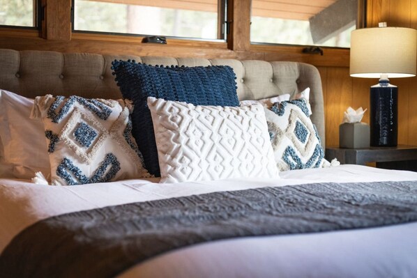 A bed with patterned pillows, a tufted headboard, and a bedside lamp.