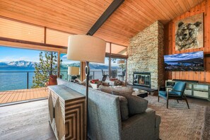 A spacious living room with a fireplace, comfortable seating, and a large TV screen displaying a scenic view.