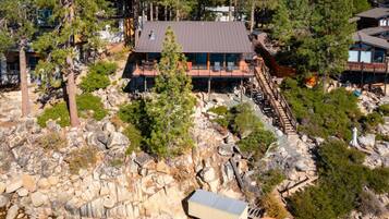 Un chalet moderne avec un toit en métal, entouré d’arbres et d’un paysage rocheux.