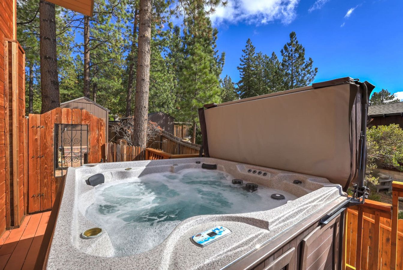 Un bain à remous doté d’une terrasse en bois et d’un espace abrité, le tout entouré d’arbres.