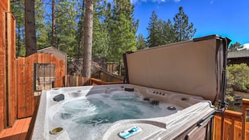 Un bain à remous doté d’une terrasse en bois et d’un espace abrité, le tout entouré d’arbres.
