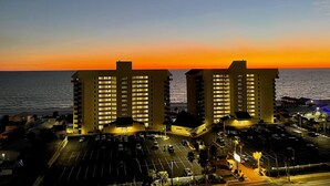 Een hotel met een parkeerplaats en uitzicht op de zonsondergang boven de oceaan.