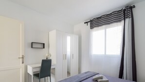 Een hotelkamer met een bed, een bureau, een stoel, een kledingkast en een raam met gordijnen.