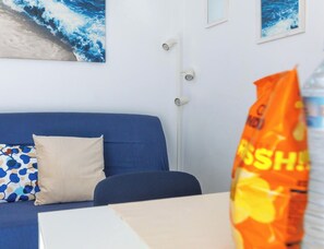 Et værelse med en blå sofa, et hvidt bord og en væg med to billeder i rammer.