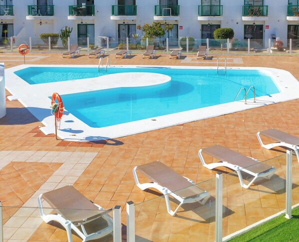 A swimming pool with lounge chairs and a lifeguard stand.