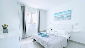 Ein modernes Schlafzimmer mit Bett, Nachttischen, einem Fenster mit Vorhängen und einem Bild an der Wand.