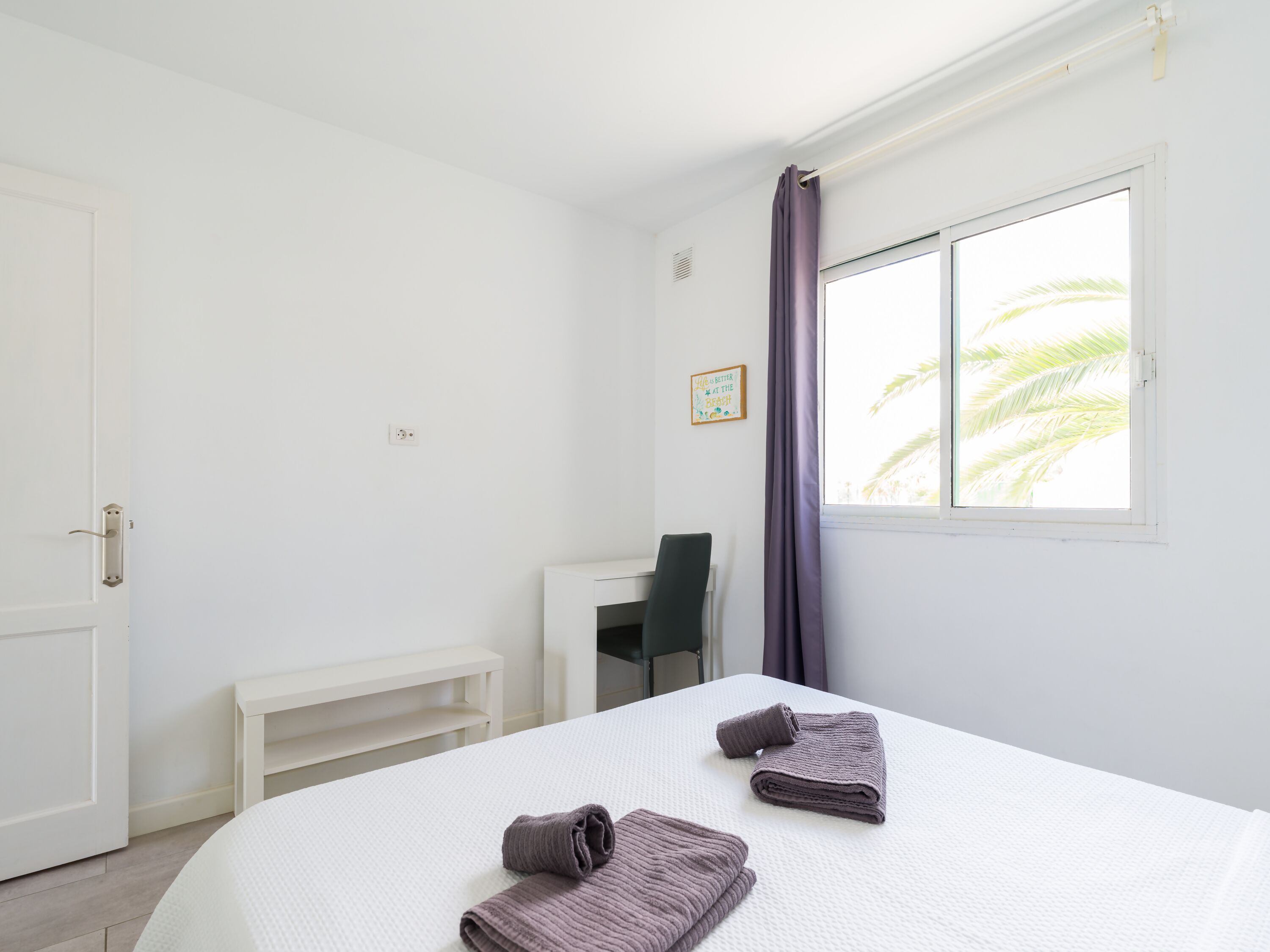 Een hotelkamer met een bed, een bureau en een raam met gordijnen.
