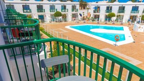 Un balcon avec vue sur la piscine, une table et une chaise.