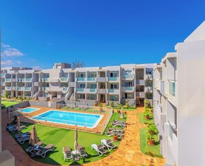A hotel with multiple balconies, a swimming pool, and sun loungers.