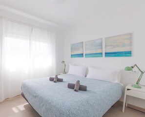 Ein Schlafzimmer mit einem Bett, einem Nachttisch, einem Spiegel und drei Bildern an der Wand.