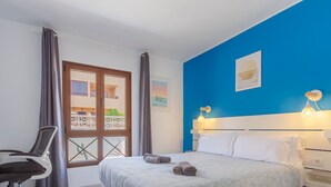 Hotellihuone, jossa on sänky, työpöytä ja ikkuna, jossa on verhot.