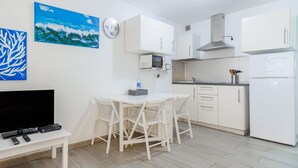 Uma cozinha moderna com armários brancos, micro-ondas e exaustor de aço inoxidável.