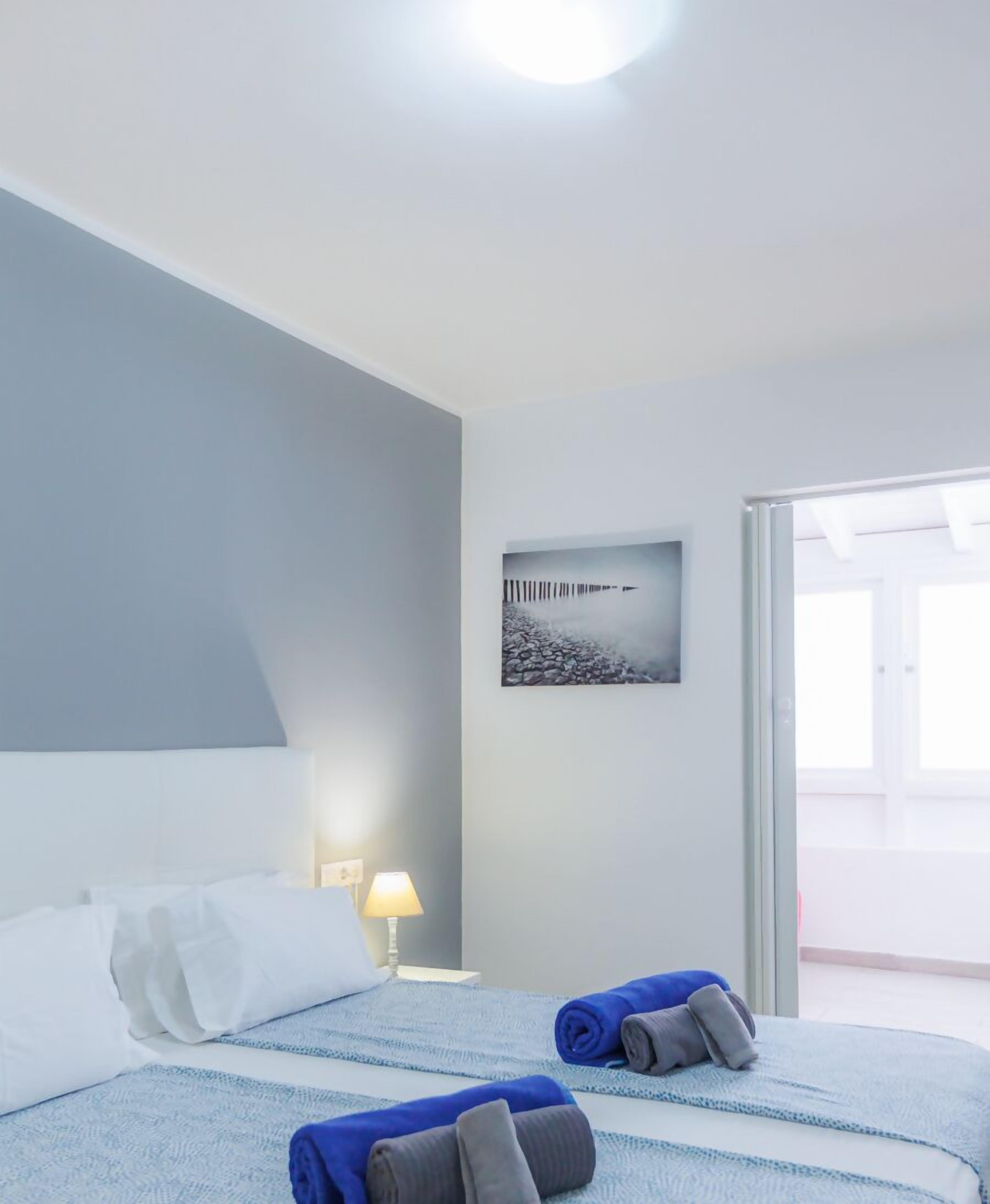 Hotelkamer met een bed, nachtkastje met lamp, een foto aan de muur en uitzicht op het exterieur.