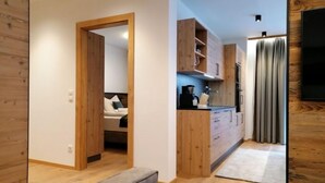 A modern kitchen with wooden cabinets, a built-in oven, and a dining area with a grey sofa.