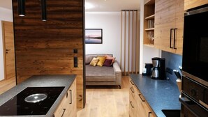 A modern kitchen with wooden cabinetry, a built-in stove, and a dining area with a sofa.