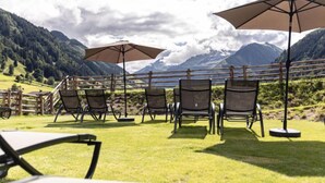 A terrace with chairs and umbrellas overlooking a mountainous landscape.