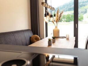 Enjoy meals in this stylish dining area with a table for two, a sofa, and a window offering a view of the surrounding landscape.