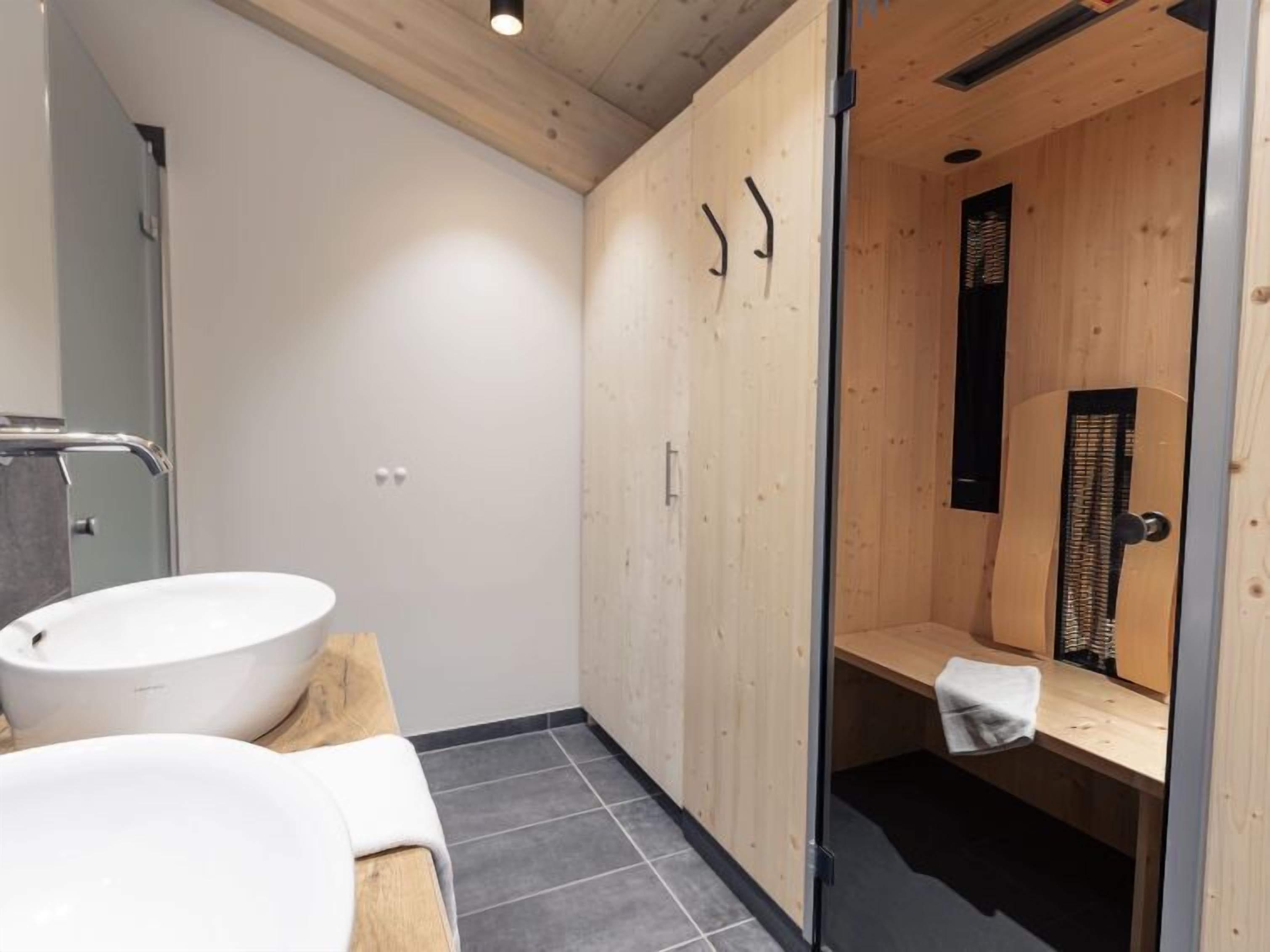Une salle de bain moderne avec un meuble-lavabo en bois, un lavabo blanc et une cabine de douche en verre.