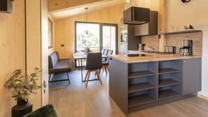 A modern kitchen with a central island, built-in appliances, and a dining area with a bench and chairs. - Superior mit 3 Schlafzimmern & IR-Sauna by Interhome (Sankt Georgen am Kreischberg)