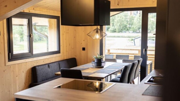 A modern kitchen with a large island, wooden walls, and a large window. - Superior mit 3 Schlafzimmern & IR-Sauna by Interhome (Sankt Georgen am Kreischberg)