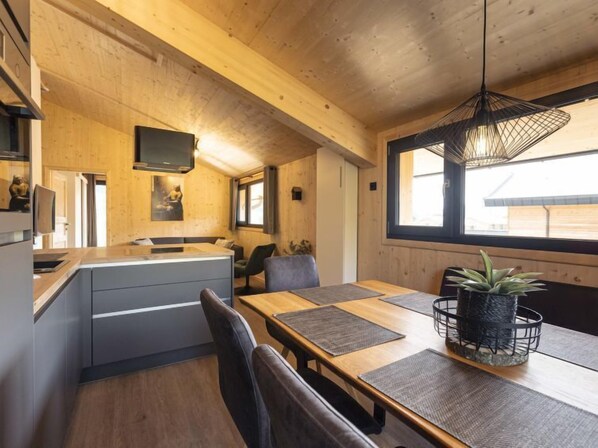 Una cocina moderna con armarios de madera, una isla integrada y un comedor con mesa y sillas de madera.