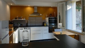 Una cocina moderna con un ventanal grande, armarios blancos y un horno empotrado.