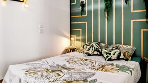 Un dormitorio con cama, lámpara colgante, planta en la pared y mesita de noche.