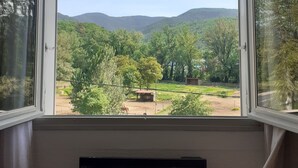 Una habitación con un ventanal grande que ofrece vistas a un paisaje verde con árboles y colinas.