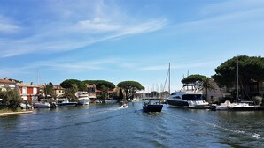 Un port de plaisance où des bateaux sont amarrés le long du quai, entouré de bâtiments et d’arbres.