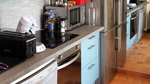Une cuisine moderne avec des meubles bleu clair, des appareils en acier inoxydable et un dosseret carrelé.