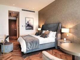 A modern hotel room with a bed, bedside table, and a chair.