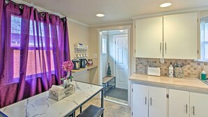 A compact kitchen with white cabinets, a marble countertop, and purple curtains. - Lovely Tacoma Cottage w/ Fire Pit, Near Dtwn! (Tacoma)