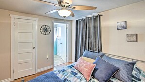 A bedroom with a bed, a ceiling fan, a door, and a view into another room. - Lovely Tacoma Cottage w/ Fire Pit, Near Dtwn! (Tacoma)