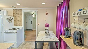 A compact kitchen with a white stove, a coffee bar, and a dining table with chairs. - Lovely Tacoma Cottage w/ Fire Pit, Near Dtwn! (Tacoma)
