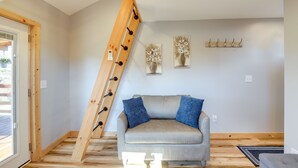 A modern living room with a wooden ladder, a grey sofa with blue cushions, and two wall-mounted paintings. - Pet-Friendly Studio w/ Hot Tub & Views in Marshall (Marshall)