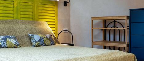 Un dormitorio con una cama, almohadas, un estante de madera y un armario azul.