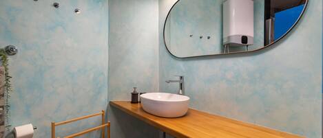 A bathroom with a wooden vanity, a white sink, a mirror, and a towel rack.