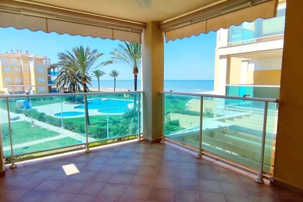 Ein Balkon mit Blick auf einen Pool und Palmen, ein Fliesenboden und ein Gebäude mit Balkonen.