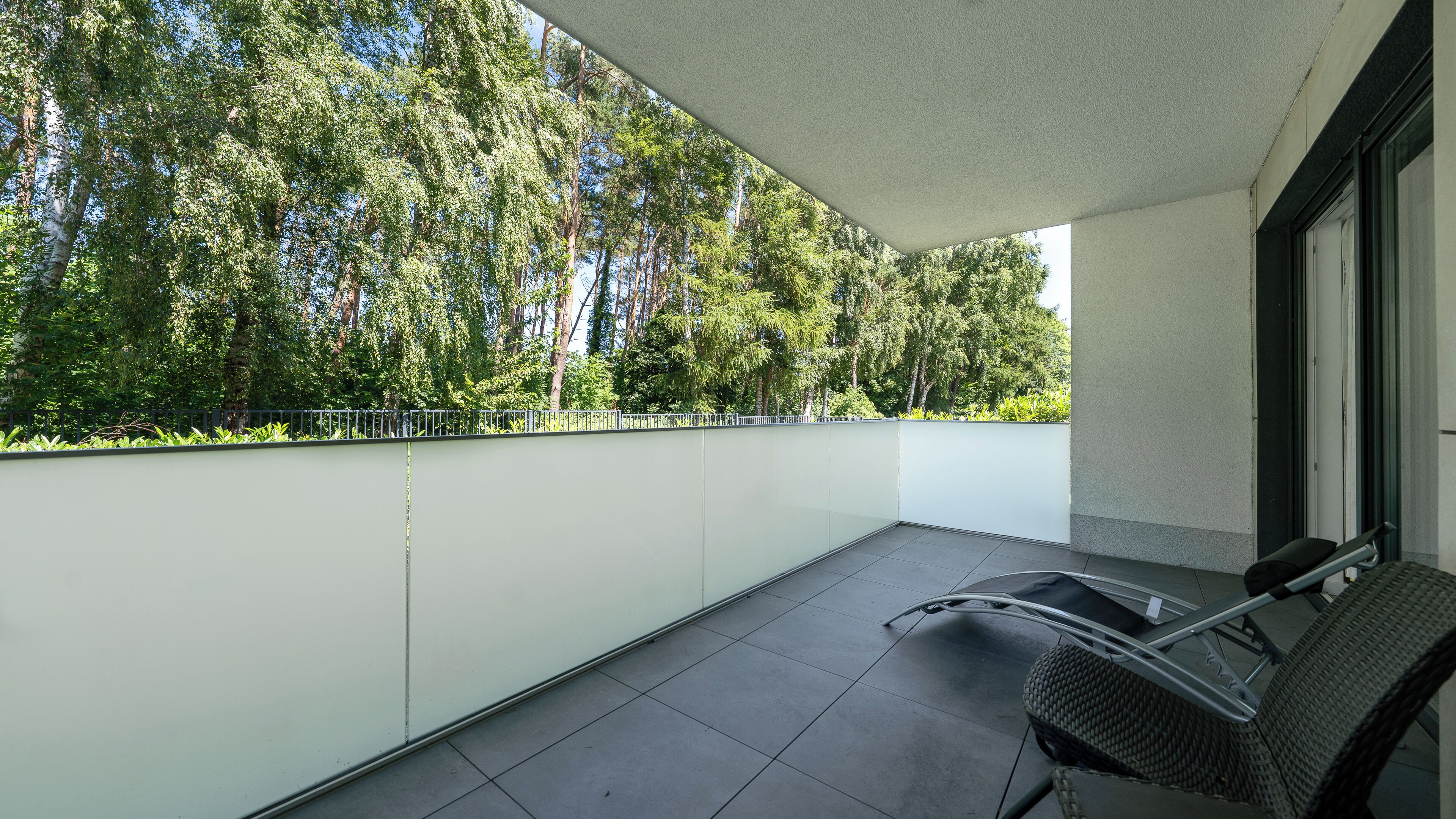 Un balcon avec une chaise, une table et une vue sur les arbres.
