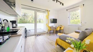 A modern kitchen with a coffee machine, a dining area with yellow chairs, a sofa, and a TV. - Sun & Snow Platinum (Rewal)