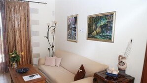 A living room with a beige sofa, a wooden coffee table, and two framed paintings on the wall. - Vasiiliki's Residence-Breathtaking View (Kissamos)