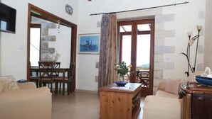 A living room with a wooden coffee table, beige sofas, and a dining area with a table and chairs. - Vasiiliki's Residence-Breathtaking View (Kissamos)